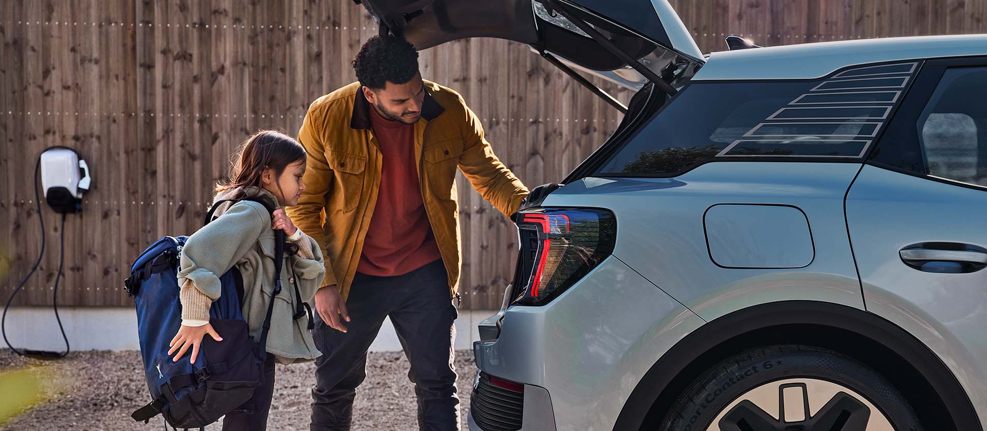 A family loading the boot of a blue electric Ford Explorer.