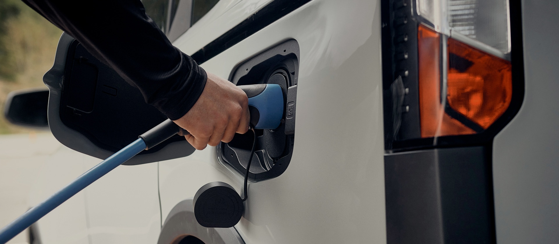 Close-up of a white Ford electric vehicle being plugged into an EV charger.