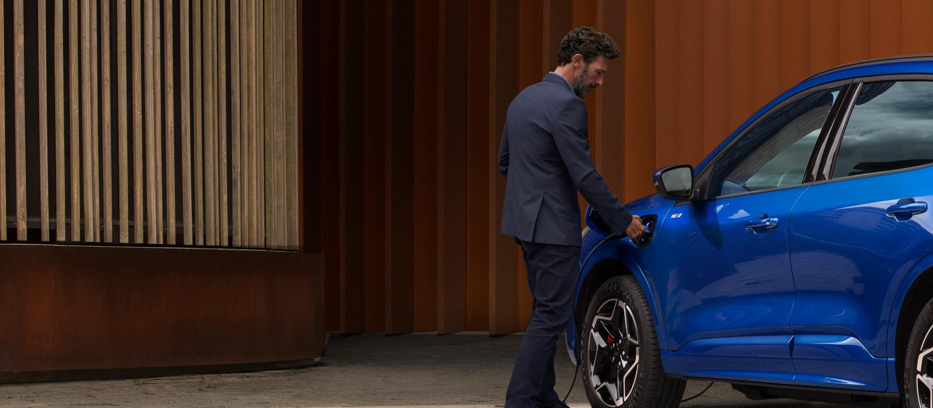 Osoba připojující plug-in hybridní vůz Ford k domácímu nabíjecímu kabelu.