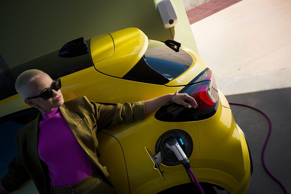 Osoba nabíjející žlutý elektromobil Ford Capri.