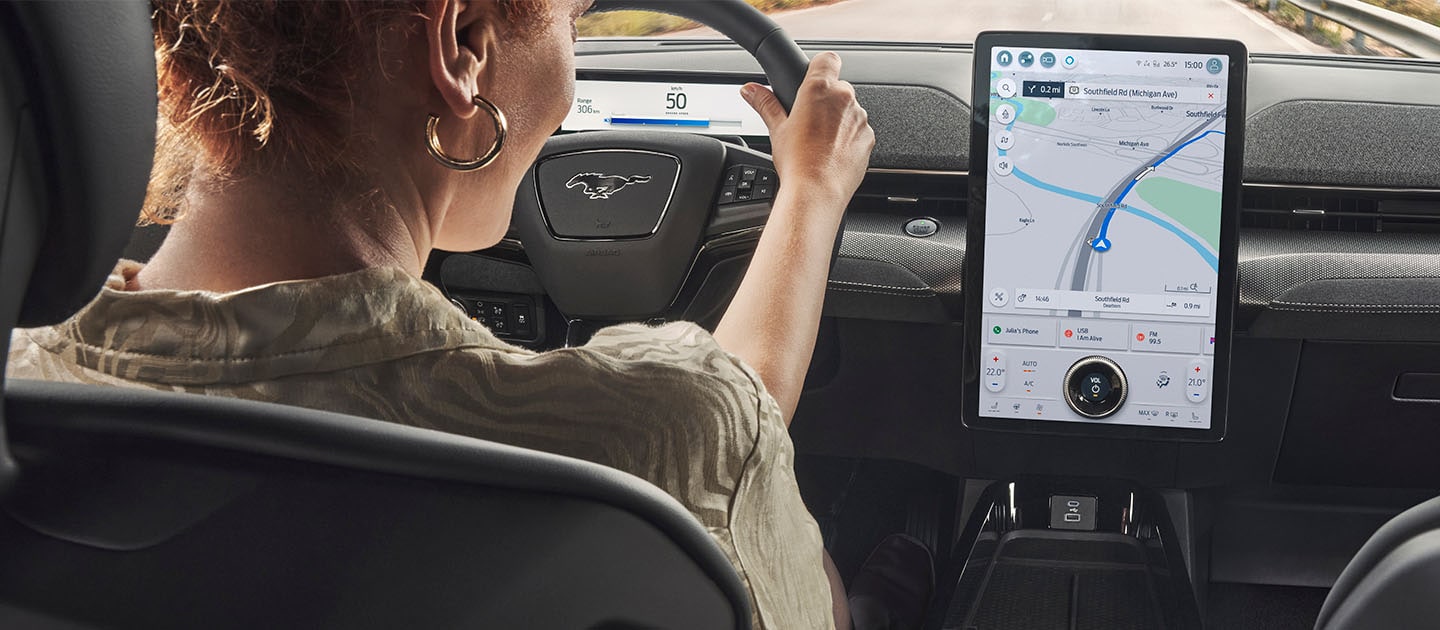 A person using sync 4 screen whilst driving a Ford mustang mach-e