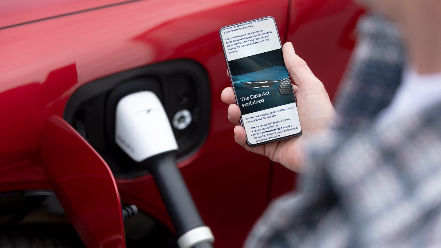 Člověk stojí vedle elektrického vozidla u nabíjecí stanice a čte si na mobilním telefonu článek vysvětlující Akt EU o datech. Člověk stojí vedle elektrického vozidla u nabíjecí stanice a čte si na mobilním telefonu článek vysvětlující Akt EU o datech.