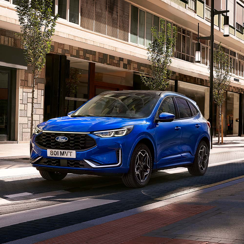 Modrý Ford Kuga jedoucí po městské ulici.